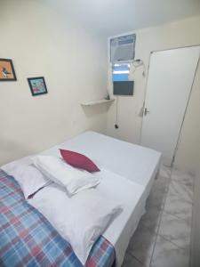 a white bed with a red pillow on it at Pousada Deus Provera in Maceió