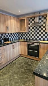 a kitchen with wooden cabinets and a black oven at Eaglescliffe Quarters in Stockton-on-Tees