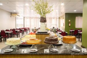 a table with cakes on it in a room with chairs at Rede Andrade Hangar in Belém