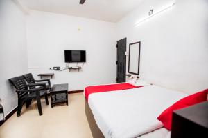 um quarto com uma cama, uma secretária e uma televisão em Hotel 1Square em Pondicherry