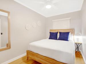 a white bedroom with a bed with blue pillows at Bubbles in the Sand in Tybee Island +38 photos