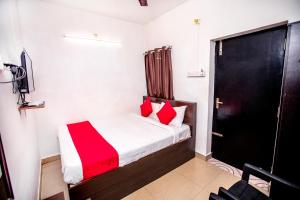 um pequeno quarto com uma cama com almofadas vermelhas em Hotel 1Square em Pondicherry
