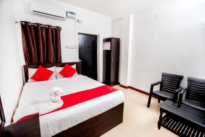 蓬蒂切里Hotel 1Square的一间卧室，有一张床，上面有红色枕头和一把椅子
