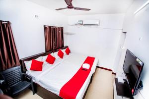 um quarto com uma cama com almofadas vermelhas e uma televisão em Hotel 1Square em Pondicherry
