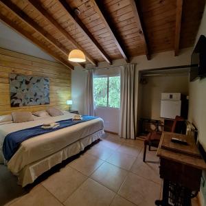 a bedroom with a large bed and a desk and a window at Hotel Antiguo Camino in Villa General Belgrano