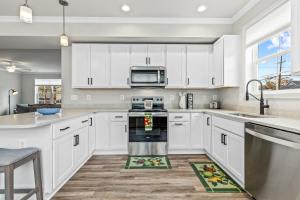 アナポリスにあるGolden Anchor Retreat Lux Living!の白いキャビネットとステンレス製の電化製品を備えたキッチン