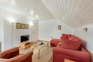 un salon avec deux chaises rouges et une télévision dans l'établissement Detached Villa Njivice Sleeps6 Stunning Views Wifi, à Igalo