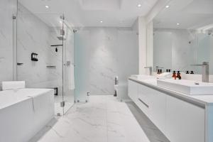 a white bathroom with two sinks and a shower at 2BR Ocean Views Condo in West Palm in Riviera Beach +31 photos
