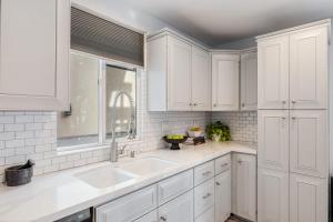 a kitchen with white cabinets and a sink at Sandy by AvantStay Oceanview Steps to Beach Patio w Fire Pit Dining Area in Newport Beach +49 photos