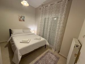 a small bedroom with a white bed and a window at Ourania's Apartment Kastoria in Mavrokhórion