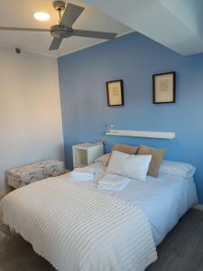 a bedroom with a white bed with a ceiling fan at Alice Home in Puebla de Farnals