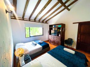 a bedroom with two beds and a television in it at Casa Colonial en el corazón de Villa de Leyva Casa serena in Villa de Leyva +13 photos
