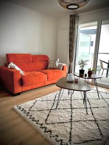 a living room with an orange couch and a rug at Appartement Vannes Odyssée in Vannes +1 photo