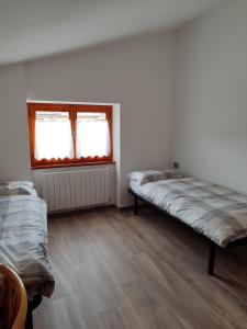 una stanza con due letti e una finestra di Sweet Home Casa Vacanze Secondo Piano a Rovetta