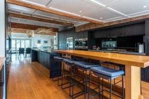 Una cocina con una barra larga con taburetes azules. en Lannan Beach House - Stay Waiheke, en Waiheke Island