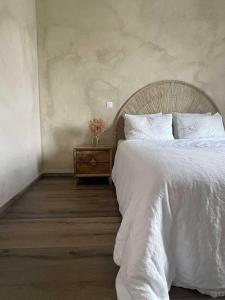 a bedroom with a white bed and a night stand at Casa Lariz in Hasselt