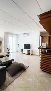 a large living room with a couch and a tv at Seaside studio with pool in Dar Bouazza