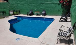 una piscina con dos sillas y una mesa en Hotel Belgrano, en Villa Carlos Paz
