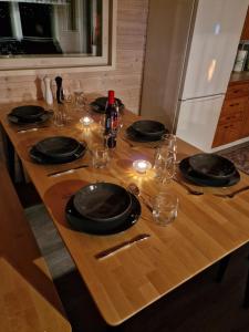 ein Holztisch mit Tellern und Weingläsern darauf in der Unterkunft Västintupa in Ranua