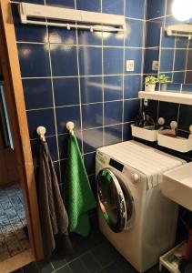 una lavatrice in un bagno con parete piastrellata blu di Apartment Misty Forest a Kranjska Gora Altre 11 foto