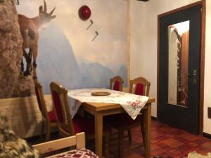 a table with chairs and a painting of a deer on the wall at Casa Gugjet Cuore Carnico - Appartamento Tamai -giardino - senza scale - parcheggio privato - 4 zampe gratis in Arta Terme