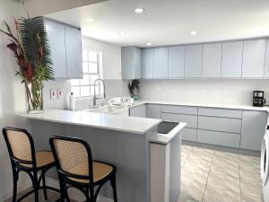 a kitchen with white cabinets and a counter with chairs at Silver Sands Beach Villas are great for family-friendly activities surfing in Christ Church