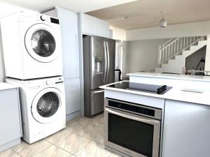 a white kitchen with a washer and dryer in it at Silver Sands Beach Villas are great for family-friendly activities surfing in Christ Church +10 photos
