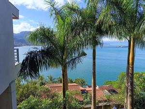 una vista del océano entre dos palmeras en Lounge Suites De Luxo Piuva, en Ilhabela