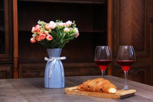a vase of flowers and a loaf of bread and two wine glasses at Old Friends Cozy House in Gyumri