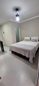 a white bedroom with a large bed with pillows at Xodó do Litoral in Caraguatatuba