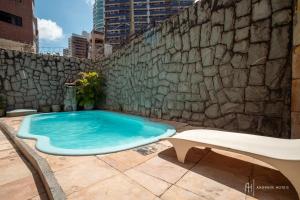 a swimming pool in front of a stone wall at Rede Andrade Coimbra in Fortaleza