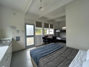 a bedroom with a bed and a table with chairs at Waikuku Beach Holiday Park in Waikuku Beach