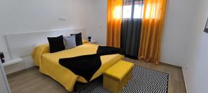 um quarto com uma cama amarela e preta e uma janela em O Infinito em Calhetas