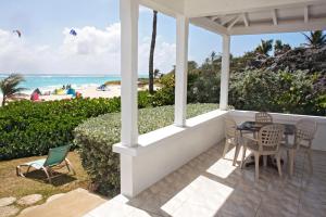 a porch with a table and chairs and the beach at ZenBreak Silver Sands Villa 2 in Christ Church