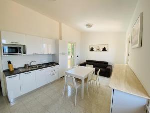 a kitchen with white cabinets and a white table at Marasusa Apartments Scirocco 226CW in Parghelia