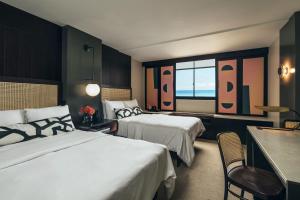 a hotel room with two beds and a table at Hotel Renew in Honolulu