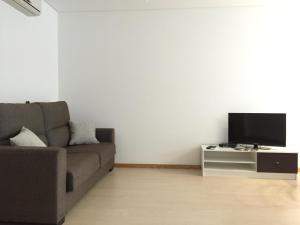 a living room with a couch and a flat screen tv at Galante Beach Apartment in Figueira da Foz