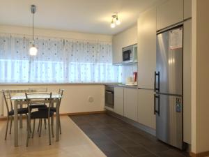 een keuken met een tafel en een koelkast bij Galante Beach Apartment in Figueira da Foz