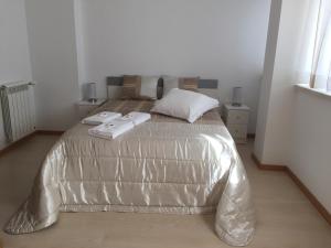 een slaapkamer met een bed met een zilveren dekbed bij Galante Beach Apartment in Figueira da Foz