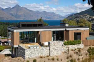 a house on a hill with mountains in the background at The Hill Residence by Sotheby's Luxury Rental Homes in Queenstown