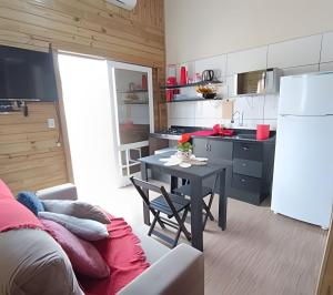 a small kitchen with a table and a refrigerator at Casa Perto das melhores praias Florianópolis, 8 pessoas, ar condicionado, tv, wifi, cozinha completa, lavanderia, in Florianópolis +79 photos