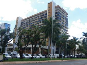a tall building with cars parked in a parking lot at IKA Apart Hotel in Brasilia