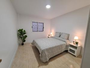 a white bedroom with a bed and a potted plant at Alojamientos KYOMU El Sol in Las Lagunas