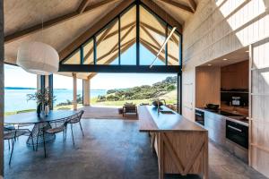a kitchen with a table and a large window at Mawhiti - Stay Waiheke in Waiheke Island