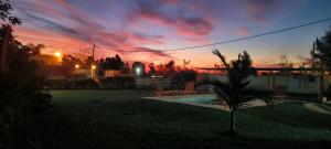una puesta de sol sobre una casa con una palmera en un patio en Angará Bungalows, en Federación