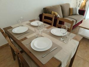 Una mesa de madera con platos y copas de vino encima. en FAIRWAYS CLUB, suite B37, en San Miguel de Abona