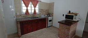 eine Küche mit einer Spüle und einer Mikrowelle auf der Theke in der Unterkunft Chalet a 500mts del mar in Mar del Tuyú + 16 Fotos