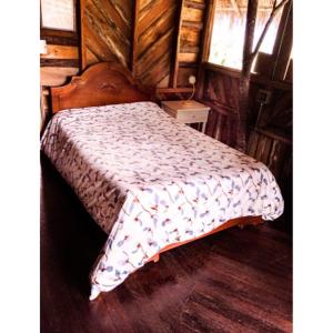 Un dormitorio con una cama en una habitación de madera. en hospedaje rural finca cafetera La Maloka, en Jardín