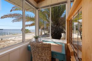 a room with windows and a desk with a view of the beach at Gulf front with sand and water access in Cedar Key +24 photos