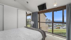 a bedroom with a bed and a large window at Beachpark Apartments - Close To Beach in Port Macquarie +4 photos